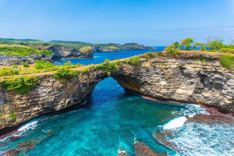 A natural rock arch spans turquoise waters at Broken Beach on Bali's coastline.