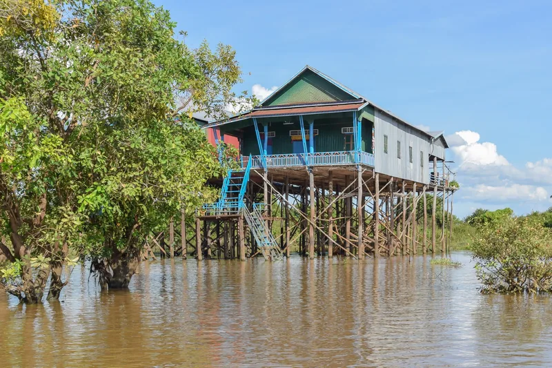 A stilt house with tall wooden supports rises above the flooded waters near Kampong Phluk, Siem Reap.