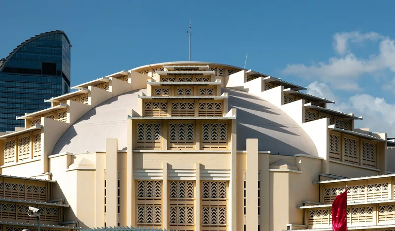 The domed art deco facade of Phsar Thmey market rises against a blue sky in Phnom Penh.