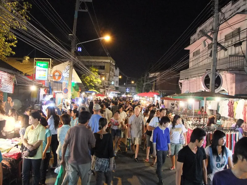 Crowds fill Chiang Mai's Walking Street night market lined with stalls and overhead wires.