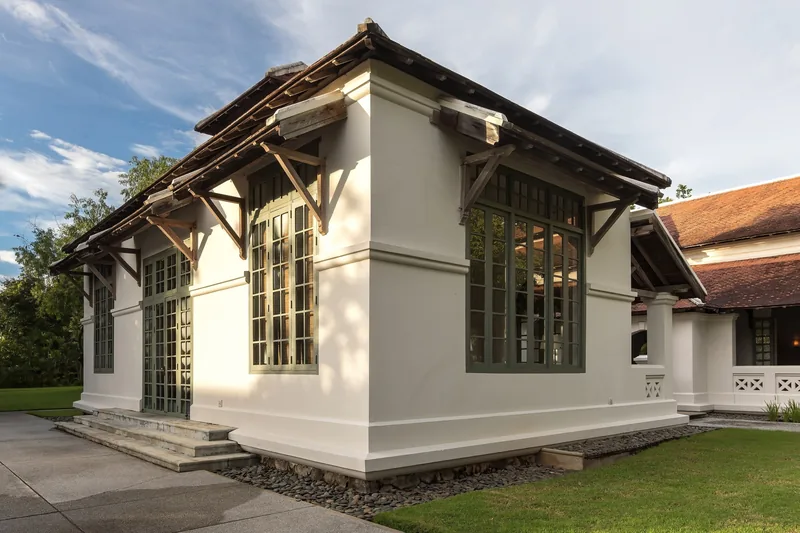 Colonial-style white building with green-framed windows and a tiled roof at a Luang Prabang resort.