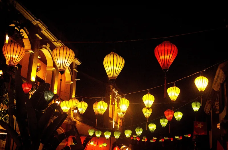Colorful silk lanterns glow above a street at night in Hoi An's old town.