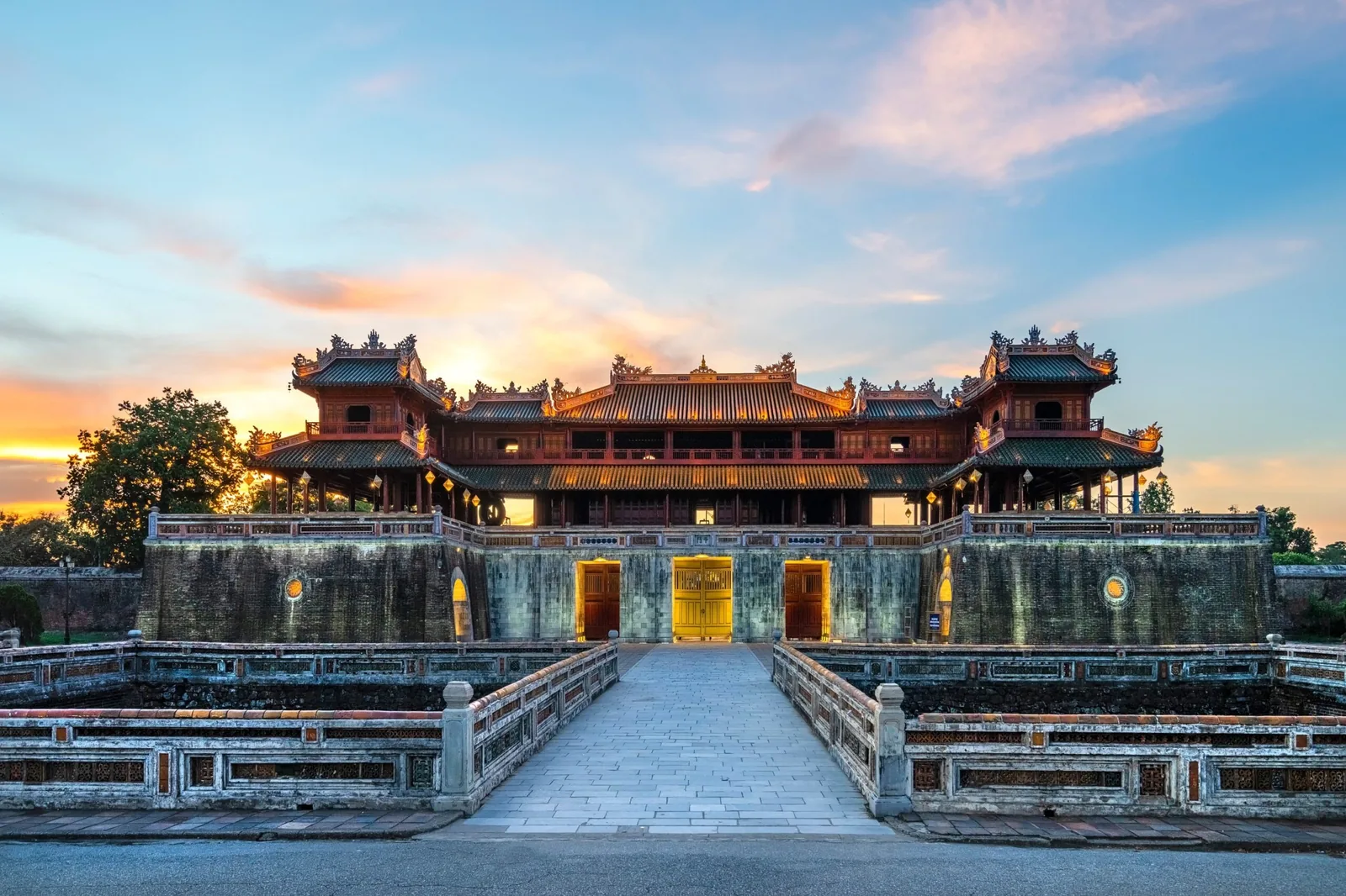 The Meridian Gate of Hue Imperial Citadel glows at sunset behind its stone bridge and moat.