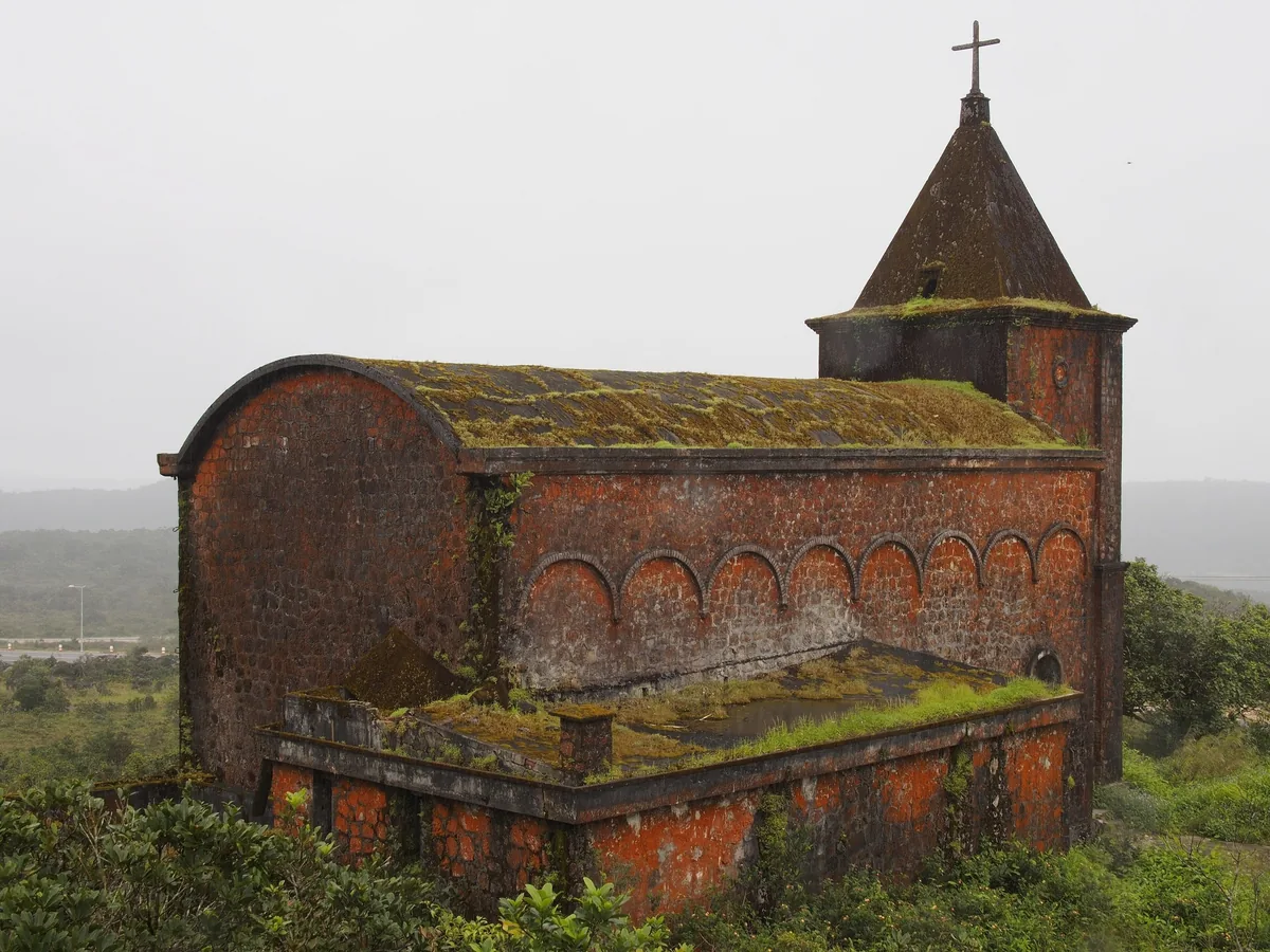 A moss-covered old red church stands amid greenery on Bokor Hill, Kampot province.