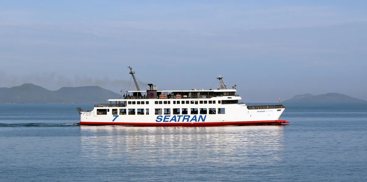 A Seatran ferry boat crosses calm waters near Koh Samui with hills in the distance.