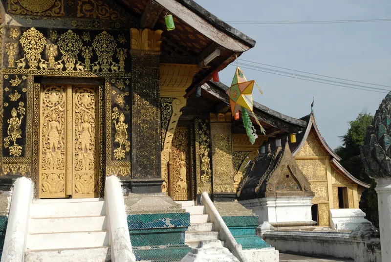 Gold-stenciled black facade and ornate stupa decorate Wat Xieng Thong temple in Luang Prabang, Laos.