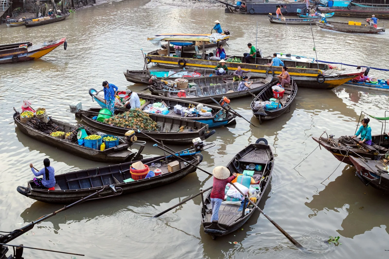 Wooden boats loaded with fruit and goods gather at a bustling floating market in the Mekong Delta.