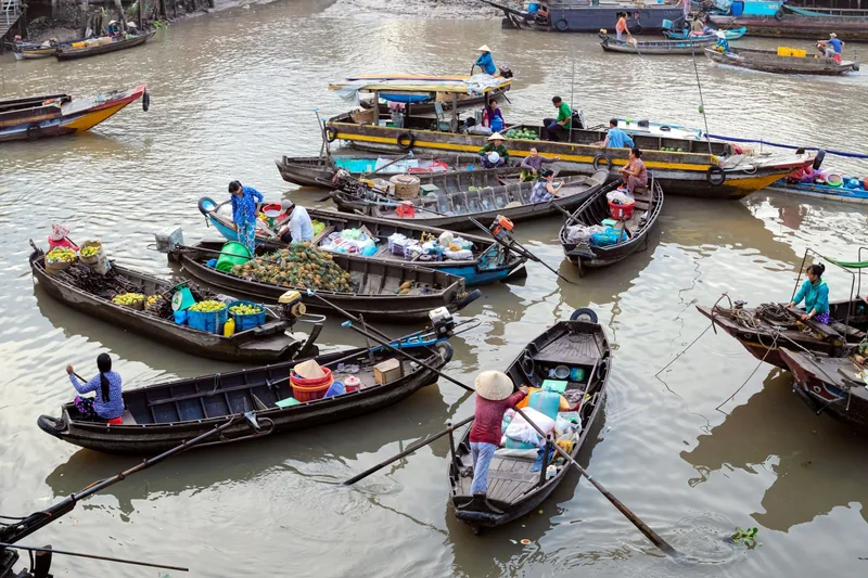 Wooden boats loaded with fruit and goods gather at a bustling floating market in the Mekong Delta.