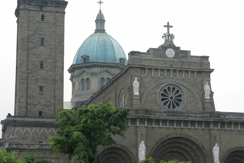 The stone bell tower, blue dome and rose window of Manila Cathedral rise above the Intramuros district.