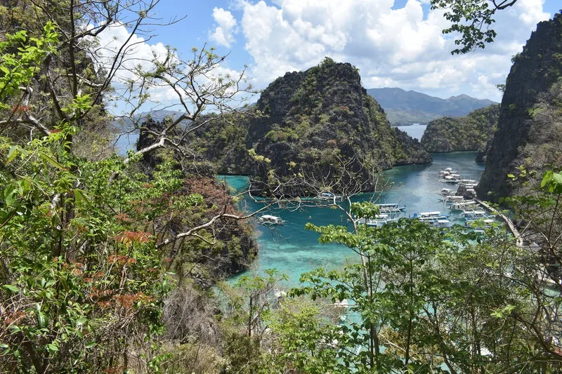 Turquoise lagoon and outrigger boats framed by limestone karst cliffs near Kayangan Lake, Coron, Palawan.