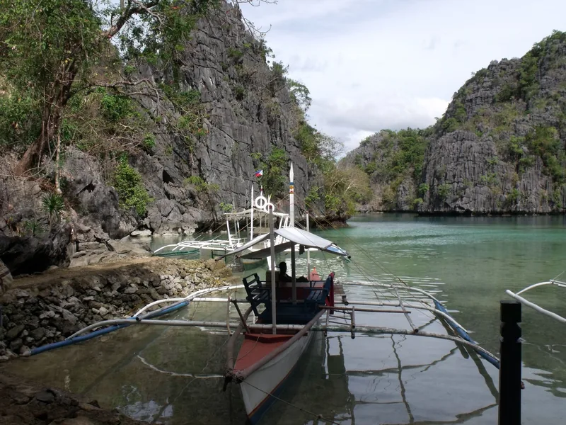 Traditional outrigger boats moored at a limestone lagoon near Kayangan Lake in Coron, Palawan.