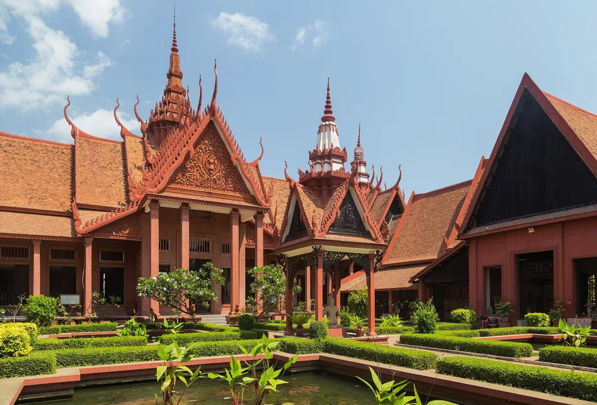 Terracotta courtyard of the National Museum of Cambodia in Phnom Penh with ornate tiered roofs and manicured gardens.