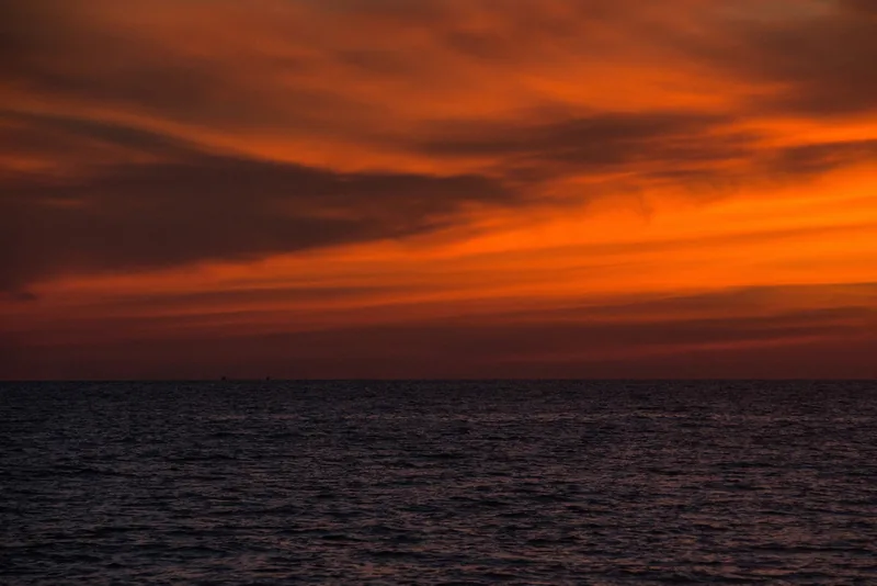 Fiery orange sunset clouds over the calm sea at Long Beach in Phu Quoc island.