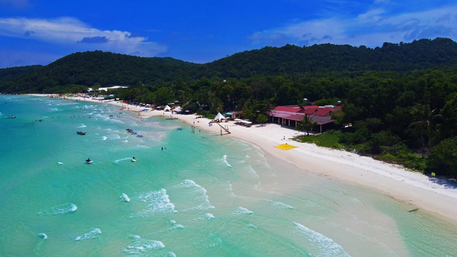 Aerial view of Bai Sao's turquoise waters and white sand lined with forested hills on Phu Quoc island.