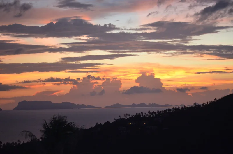 Vivid sunset over the sea with distant island silhouettes seen from a hillside on Koh Samui, Thailand.