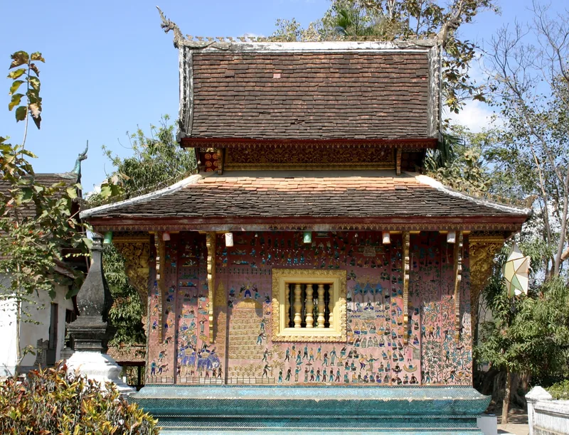 A mosaic-covered chapel with layered tiled roofs stands at Wat Xieng Thong in Luang Prabang.