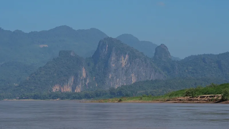 Limestone karst mountains rise above the muddy Mekong River near Luang Prabang, Laos.