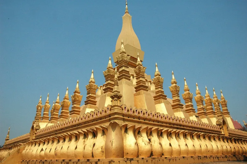 Golden tiered spires of Pha That Luang stupa rise against a clear blue sky in Vientiane.