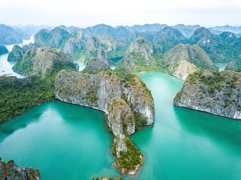 Aerial view of limestone karsts rising from turquoise waters in Ha Long Bay, Vietnam.