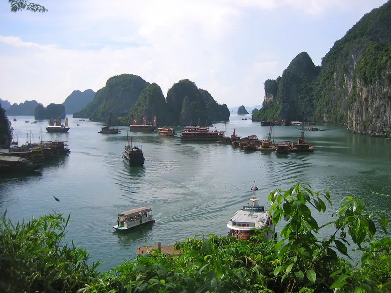 Cruise boats and junks dot the emerald waters among limestone karsts in Ha Long Bay, viewed from Surprise Cave.