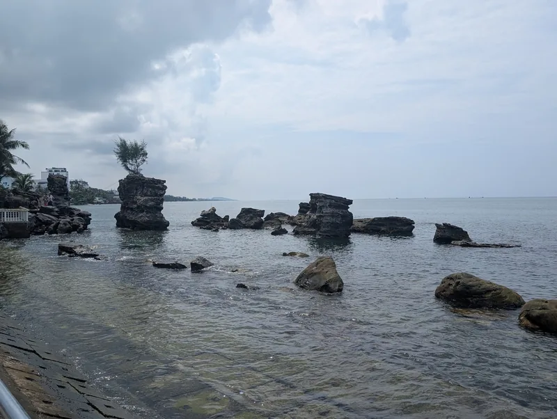 Rock formations rise from shallow coastal waters under a cloudy sky in Phu Quoc.