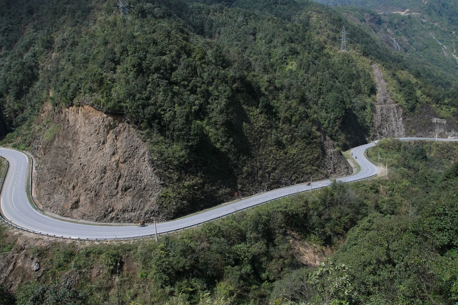 A winding mountain road cuts through forested slopes near Y Ty, Lao Cai province.