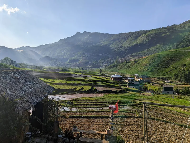 Terraced fields and a thatched-roof house stretch across a mountain valley at sunrise in Sapa, Vietnam.